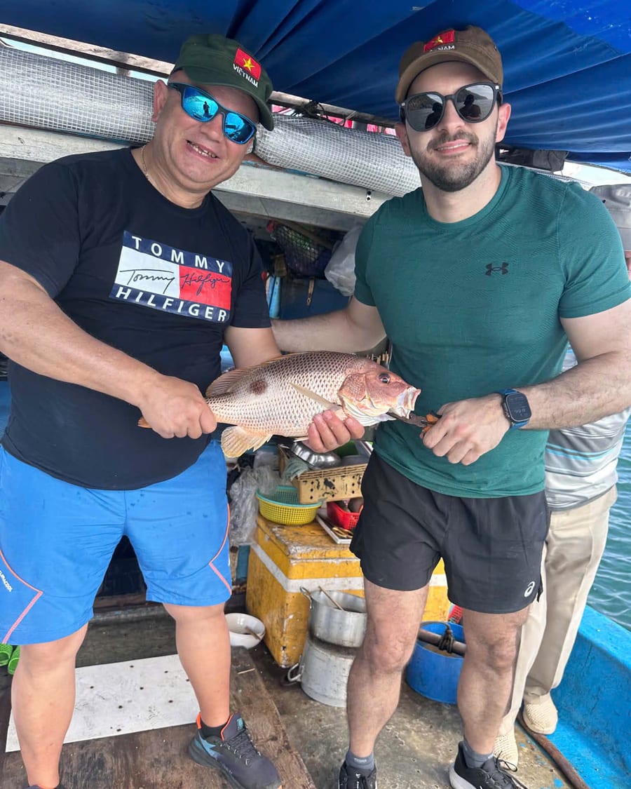 Two guests holding a fish caught on a Da Nang fishing tour